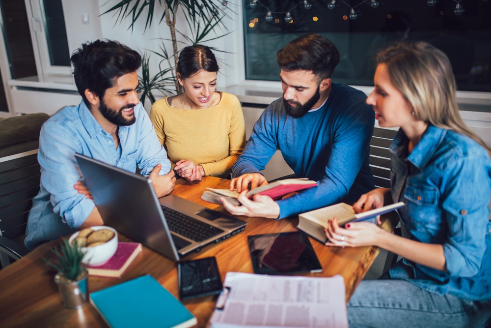 Groupe étudiant autour d'un ordinateur portable et de livres.