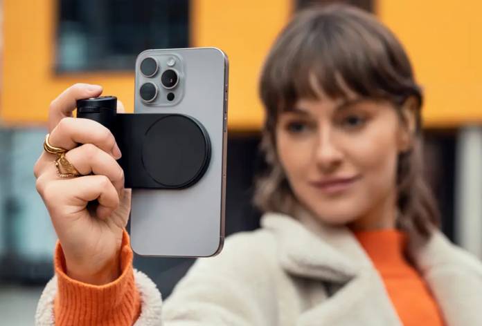 Femme prend selfie avec smartphone et accessoire.