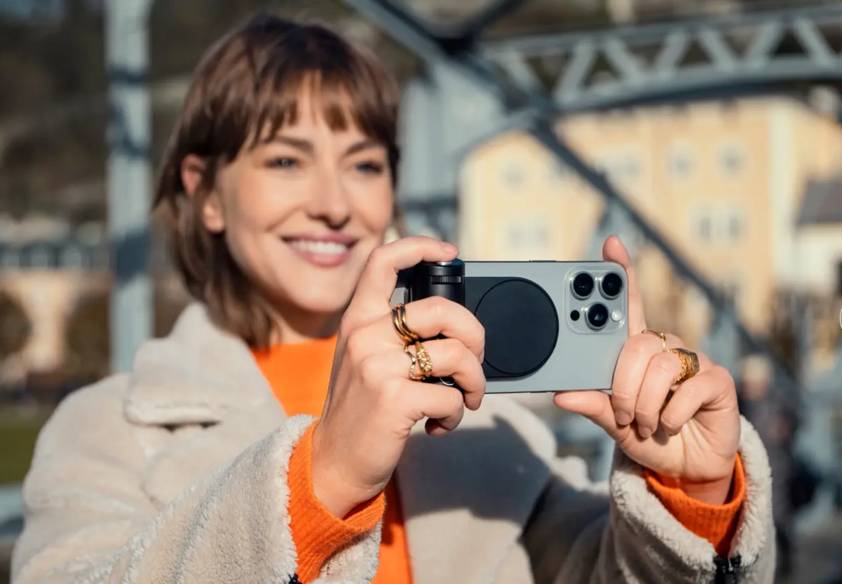 Personne photographie avec smartphone sur un pont.