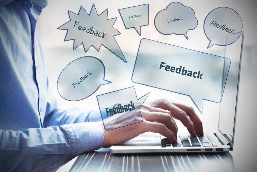 Mains tapant sur clavier, bulles de dialogue 'feedback'.