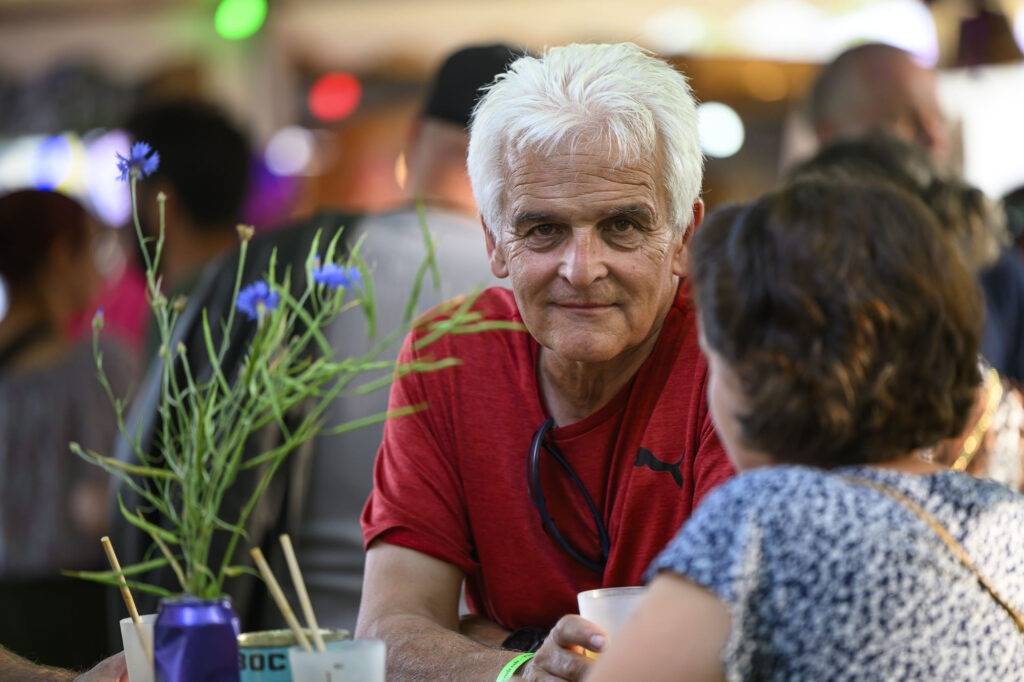 Homme discutant dans un café, fleurs en avant-plan.