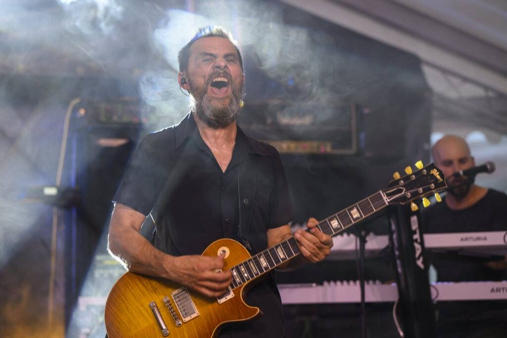 Guitariste jouant sur scène en concert énergique.