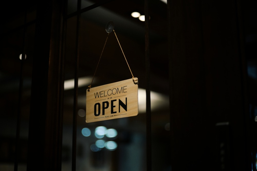 Panneau suspendu disant 'Bienvenue, Ouvert'.
