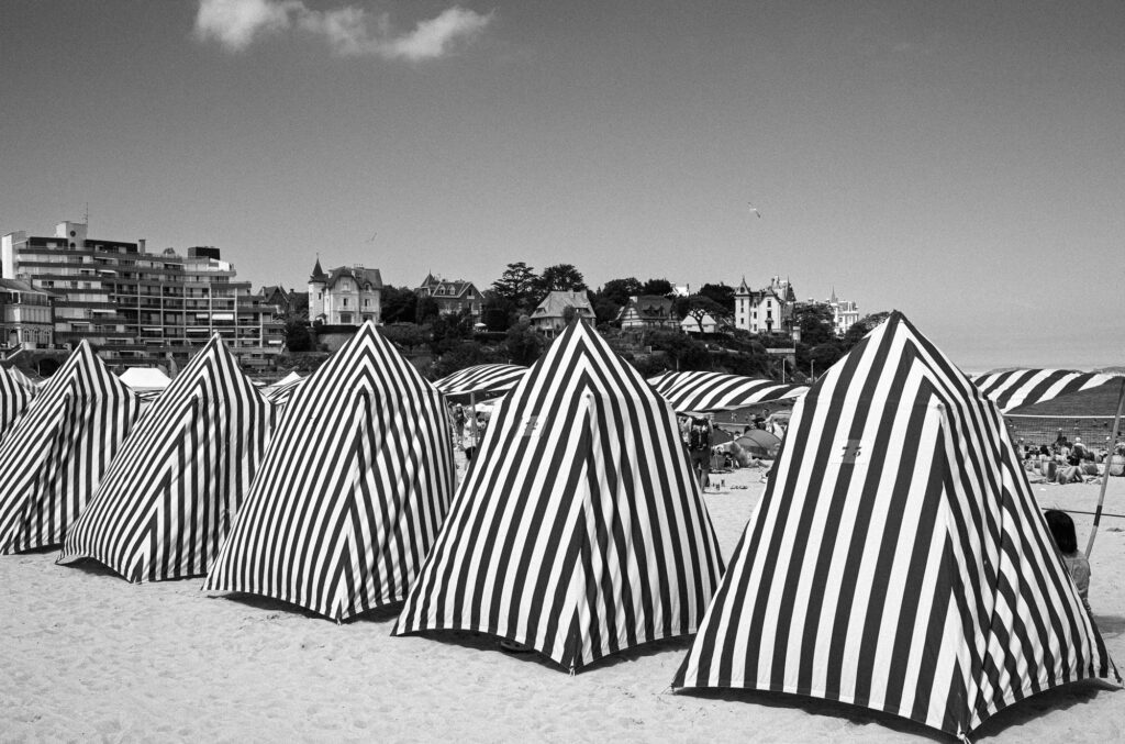 Tentes rayées sur plage urbaine ensoleillée.