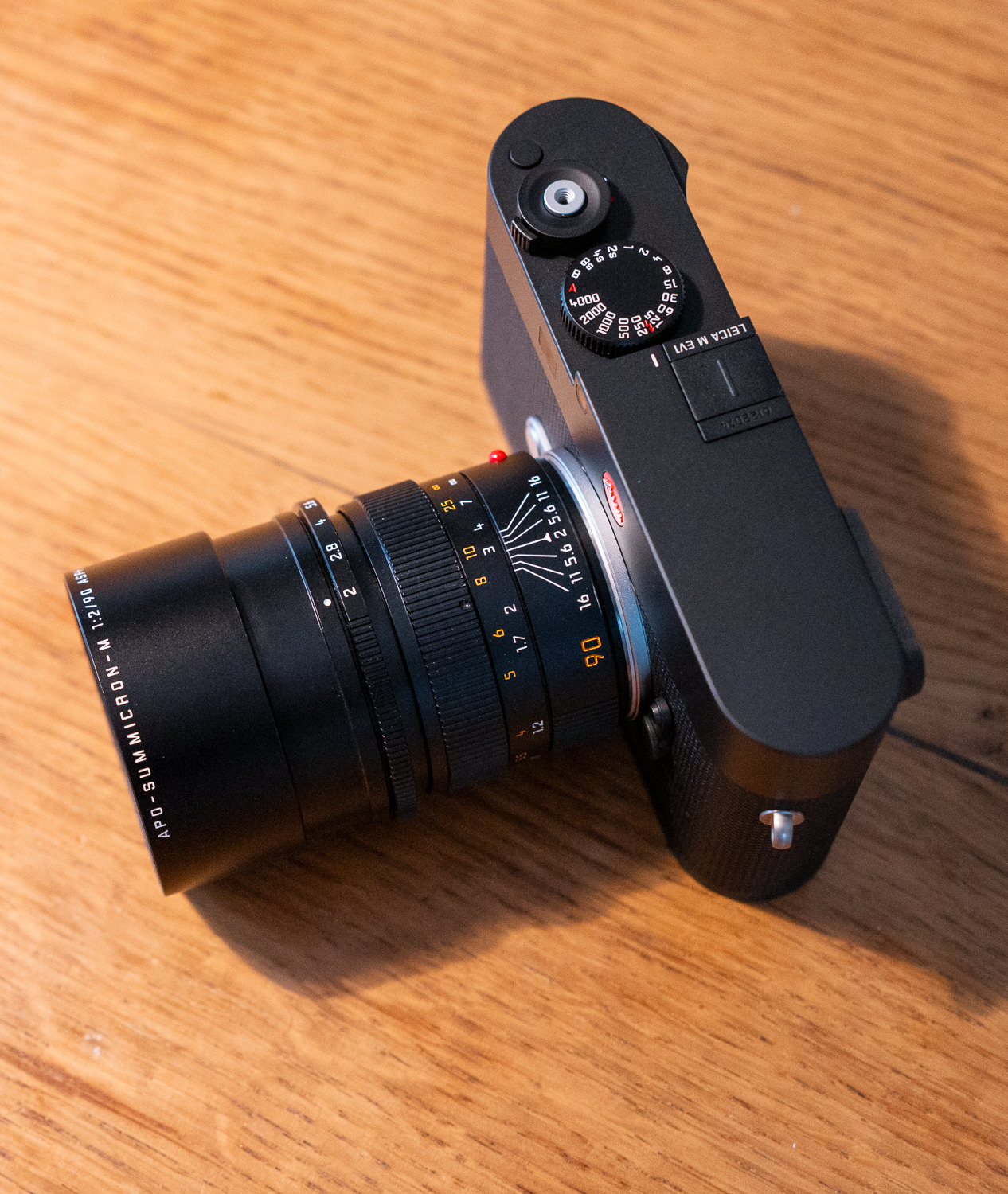Appareil photo noir avec objectif, sur table en bois.