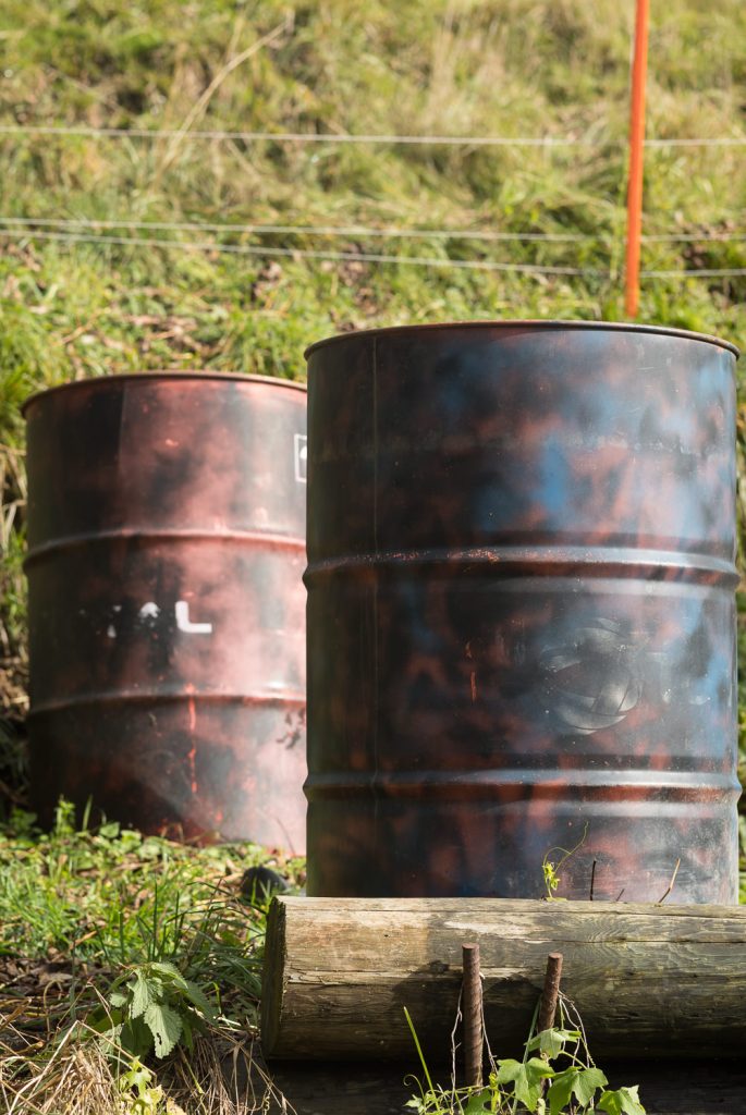 Deux fûts métalliques rouillés dans l'herbe.