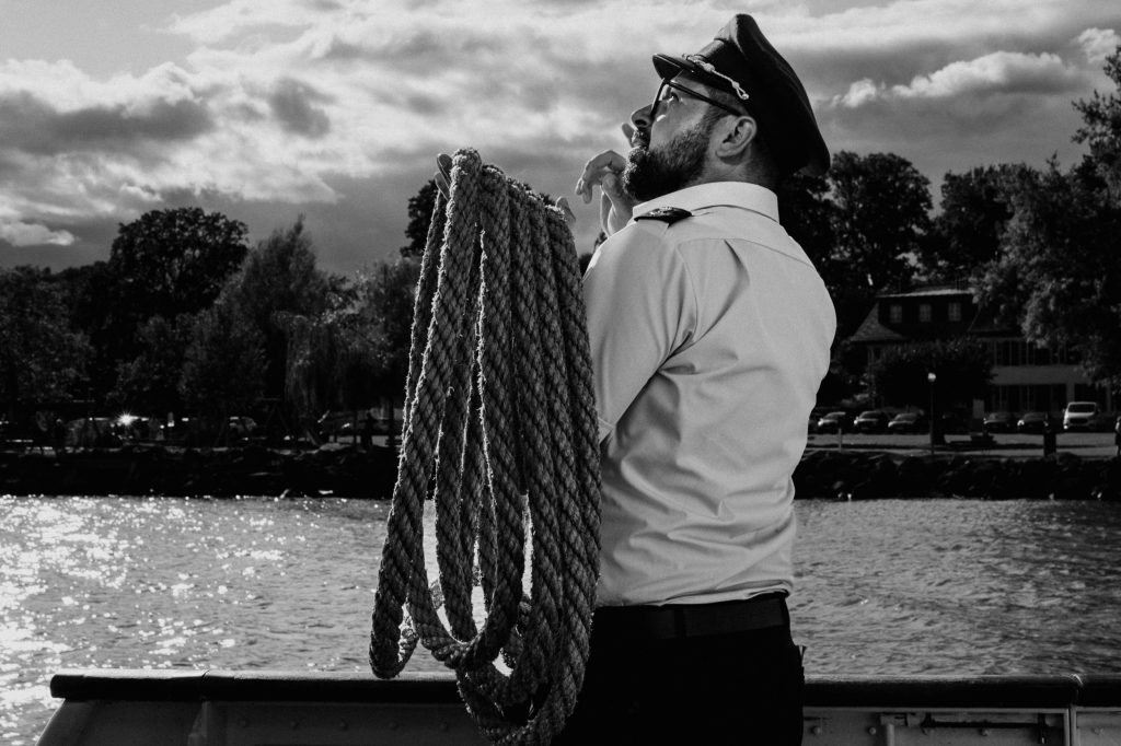 Capitaine sur un bateau tenant une corde, jour nuageux.