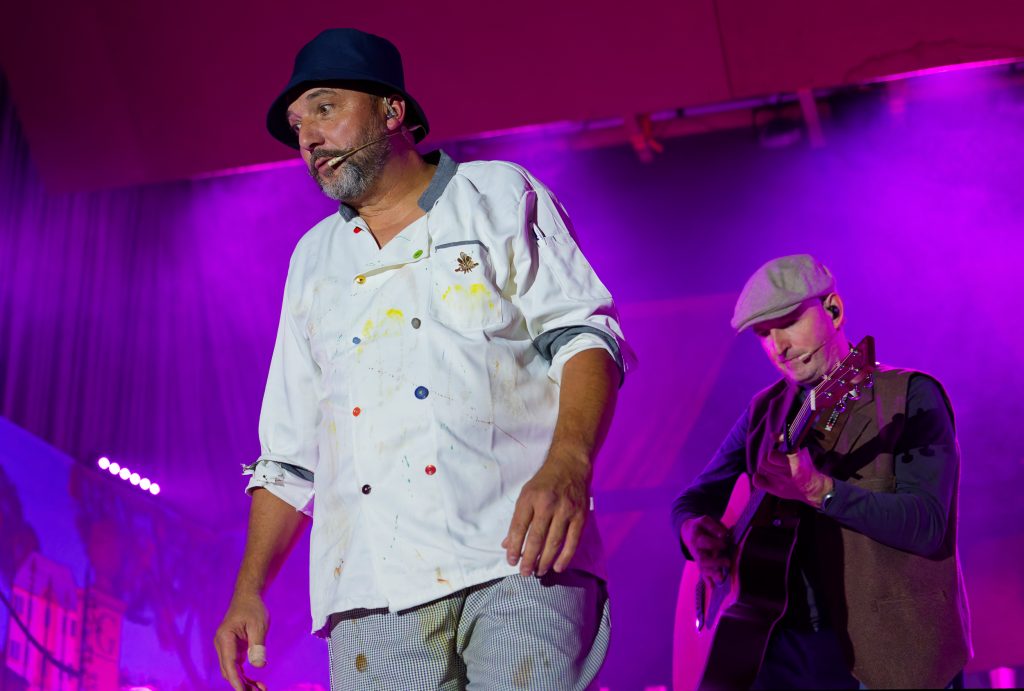 Deux musiciens sur scène avec lumières violettes.