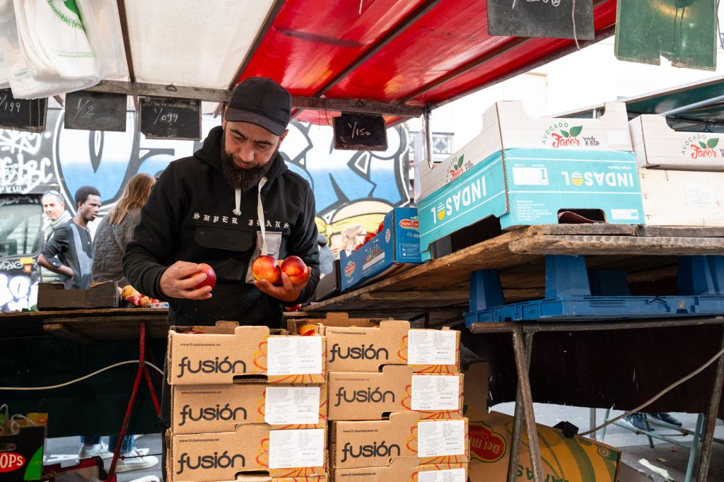 Homme choisissant des fruits au marché en plein air.