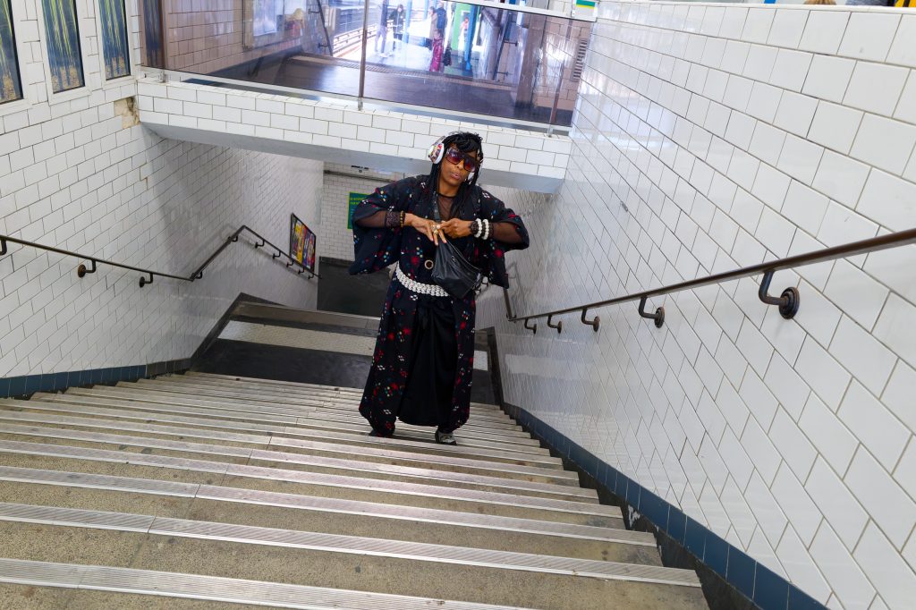 Personne habillée de façon colorée dans un escalier souterrain.