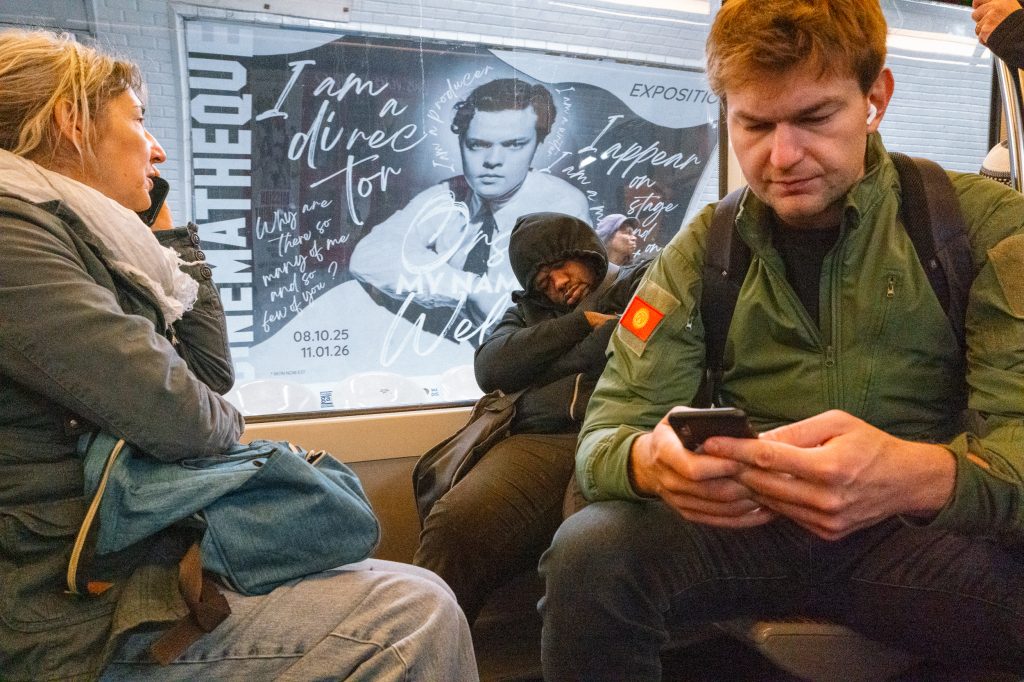 Personnes assises dans le métro devant une affiche