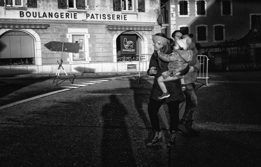Famille traversant devant boulangerie.