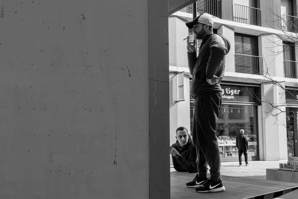 Homme debout fumant devant un magasin.