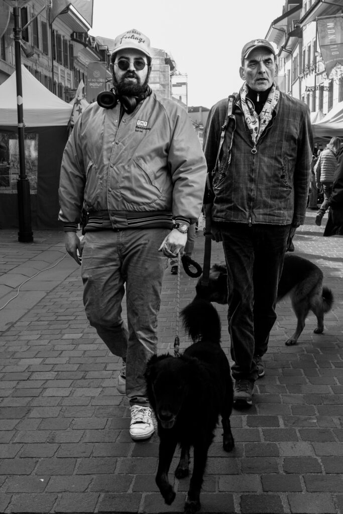 Deux hommes marchent avec des chiens en ville