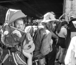 Homme portant enfant en sac à dos foule