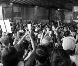 Foule manifestant sous un pont, smartphones levés